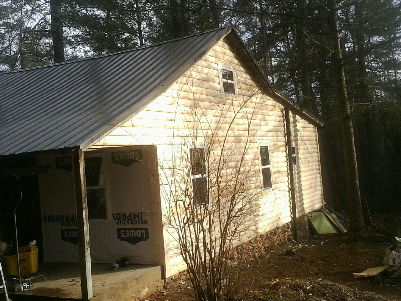 Log siding gable end under a dark metal roof edge in Acton